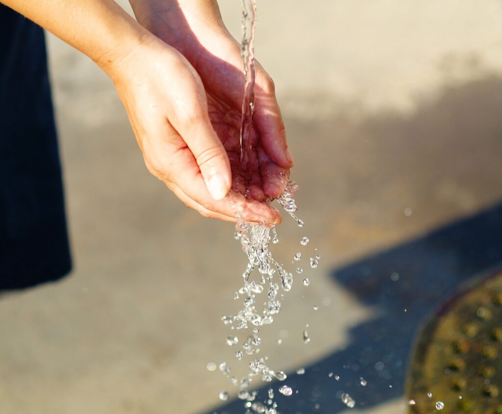 manos mojándose bajo un chorro de agua