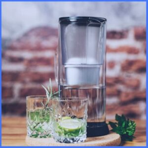 Jarra con filtro de agua Silberthal al lado de dos vasos con agua y limón
