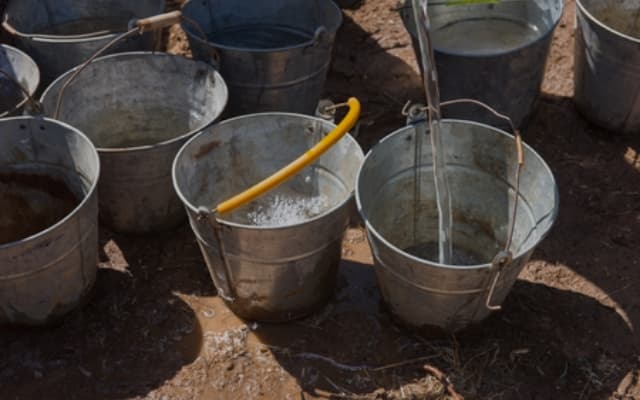 Varios cubos metálicos llenándose de agua