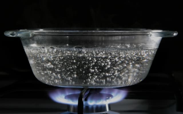 Ebullición de agua en un recipiente de vidrio con fogón 