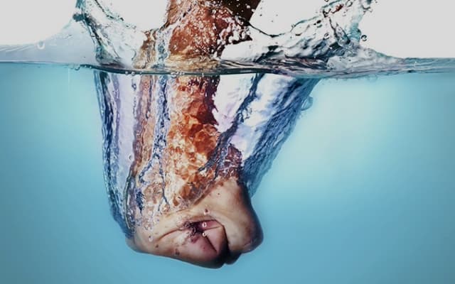 Puño cerrado sumergiéndose con fuerza en el agua