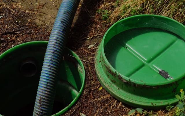 Hoyo con revestimiento de plástico y una manguera de una bomba para sacar agua de un pozo